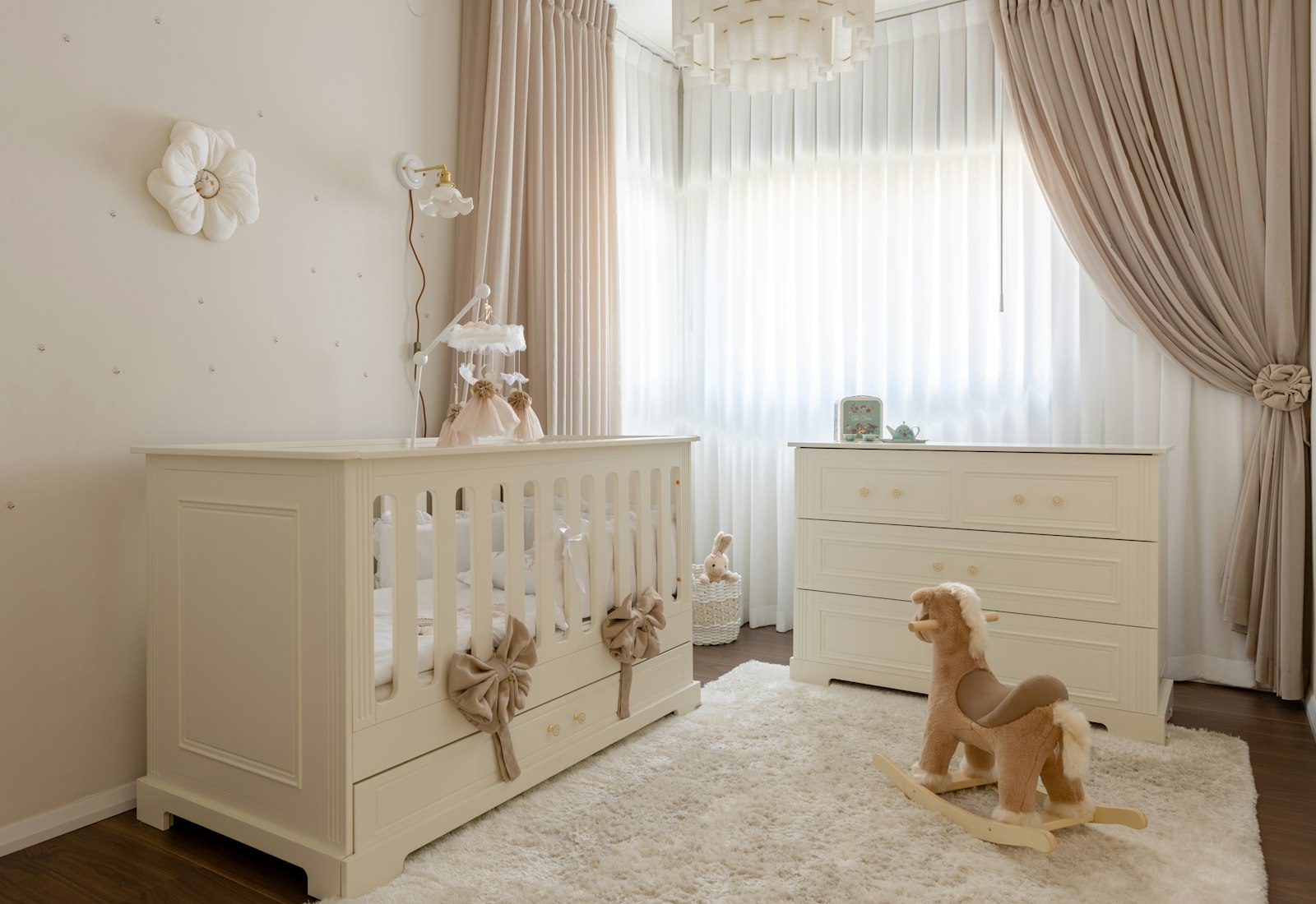 Nursery bayi bernuansa krem dengan tempat tidur, laci, dan kuda mainan